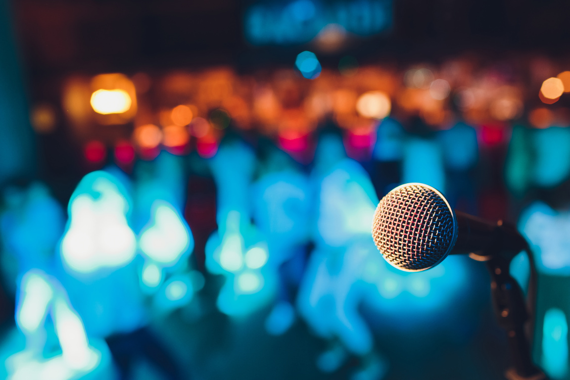 microphone on a stand up comedy stage with colorful bokeh, high contrast image.